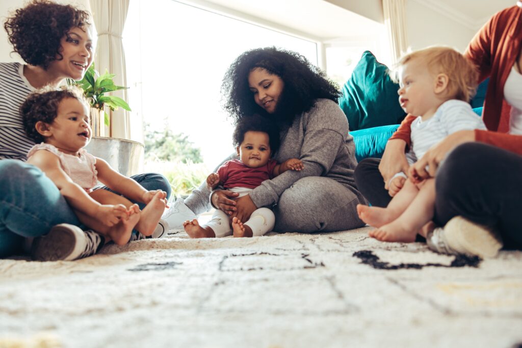 Group of moms and young children connecting while sitting in the floor of a house